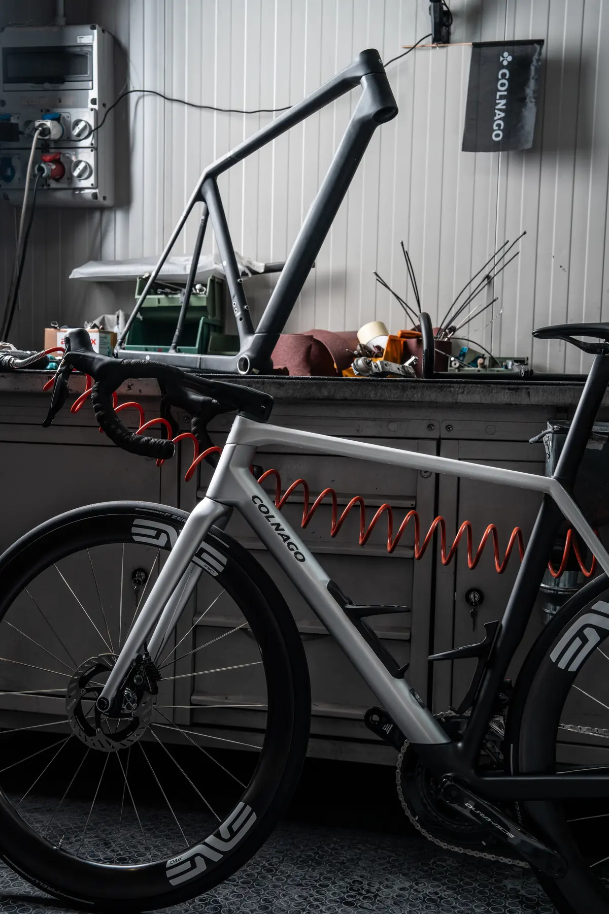 Bar Colnago C72-ram på verkstadsbänken med en färdigbyggd Colnago framför